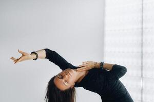 A girl in a black dress moves in a dance on a gray background. Dynamic dance photo