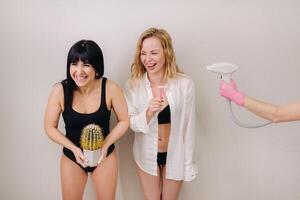 Cactus concept. Unshaven body . One girl is holding a cactus in her hands, and the second girl is holding a razor. Symbol of unshaven body parts photo