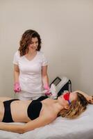 A doctor does laser hair removal for a client of unwanted facial hair in a beauty salon photo
