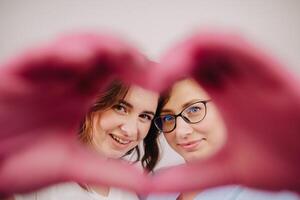 Portrait of two qualified cosmetologists-women, confidently smiling and making a heart with their hands in a medical center photo