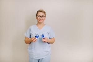 a female laser hair removal master in a blue robe holds shaving machines on a light background photo