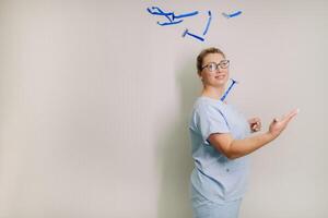 a female laser hair removal master in a blue robe throws shaving machines on a light background photo