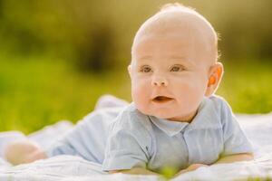 Cute happy toddler lying on a blanket on the grass outdoors in summer photo