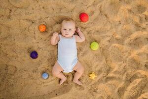 Top view of a happy little boy lying on a sandy beach photo