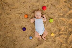 Top view of a happy little boy lying on a sandy beach photo