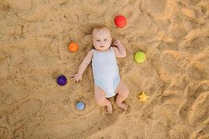 Top view of a happy little boy lying on a sandy beach photo