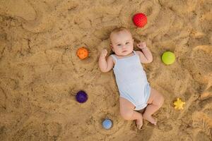 Top view of a happy little boy lying on a sandy beach photo