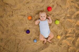 Top view of a happy little boy lying on a sandy beach photo