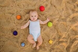 Top view of a happy little boy lying on a sandy beach photo