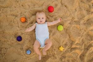 Top view of a happy little boy lying on a sandy beach photo