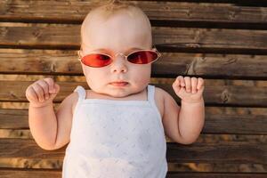 Top view of a happy little boy with glasses lying on a wooden sunbed photo