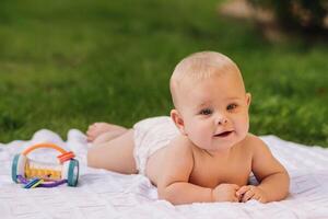 Cute happy toddler lying on a blanket on the grass outdoors in summer photo