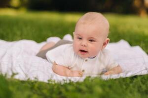 Cute happy toddler lying on a blanket on the grass outdoors in summer photo