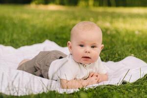 Cute happy toddler lying on a blanket on the grass outdoors in summer photo