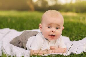Cute happy toddler lying on a blanket on the grass outdoors in summer photo