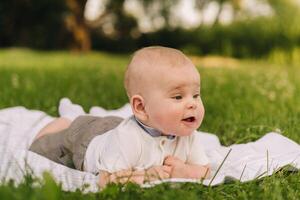 Cute happy toddler lying on a blanket on the grass outdoors in summer photo