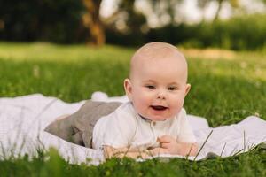 Cute happy toddler lying on a blanket on the grass outdoors in summer photo