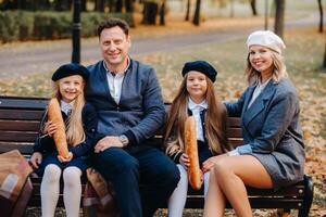 A large family is sitting on a bench in an autumn park. Happy people in the autumn park photo
