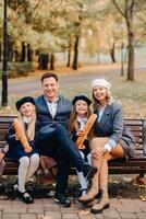 A large family is sitting on a bench in an autumn park. Happy people in the autumn park photo