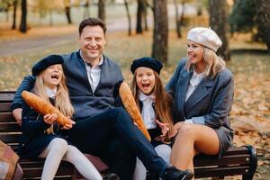 A large family is sitting on a bench in an autumn park. Happy people in the autumn park photo