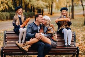 A large family is sitting on a bench in an autumn park. Happy people in the autumn park photo