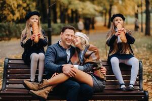 A large family is sitting on a bench in an autumn park. Happy people in the autumn park photo