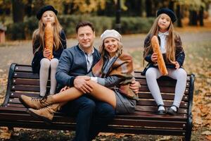 A large family is sitting on a bench in an autumn park. Happy people in the autumn park photo