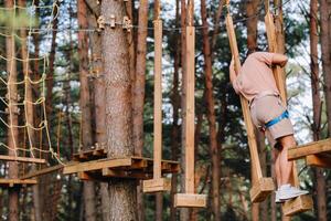 A man overcomes an obstacle in a rope town. A man in a forest rope park photo