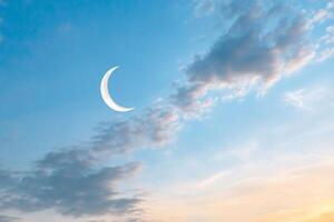 The crescent moon is seen in the sky with clouds photo