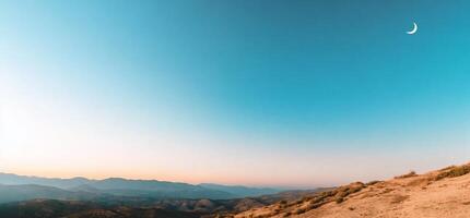 A view of the moon and the mountains at sunset photo