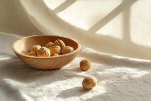 A wooden bowl with walnuts on a white cloth photo