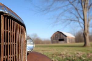 A close up of an old rusty car with a barn in the background photo
