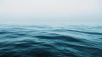 The ocean is calm and peaceful, with no signs of life. The water is a deep blue color, and the sky is a light gray. The scene is serene and tranquil, with no distractions or disturbances photo