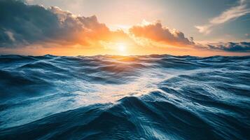 The ocean is calm and the sun is setting, creating a beautiful and serene atmosphere. The water is a deep blue color, and the sky is filled with clouds, adding to the peacefulness of the scene photo
