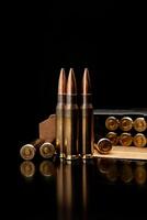 Three rifle bullets standing upright with a box of ammunition in the background, brass casings and copper-colored tips, reflective black surface. photo