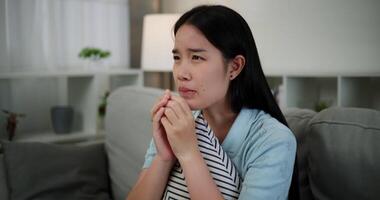 Handheld shot, An attractive young woman is intently watching something on TV and shows signs of extreme excitement and joy while sitting on sofa in the living room at home. video