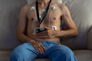 debt defaulting crisis concept. Male patient wearing a portable heart monitor with electrodes attached to the chest. Holter device is used for health diagnostics and monitoring cardiac activity. photo