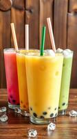 Colorful bubble teas with different flavors served in clear glasses on a wooden table photo