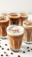 Delicious assortment of creamy coffee beverages arranged on a white surface with coffee beans scattered around photo