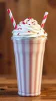 Creamy milkshake topped with whipped cream and sprinkles served in a striped glass with two colorful straws photo