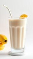 Refreshing banana smoothie served in a tall glass beside fresh bananas on a light background photo