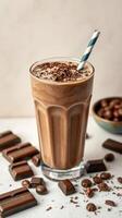Creamy chocolate milkshake topped with chocolate shavings next to chocolate bars and sweets photo