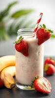 Creamy banana strawberry smoothie with fresh fruit and a striped straw served in a glass photo