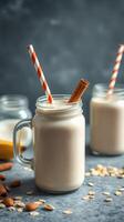 Creamy almond milkshake with cinnamon and striped straws served in mason jars on a textured background photo