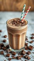 Chocolate milkshake with decorative straws and chocolate pieces on a marble surface, captured in warm lighting photo