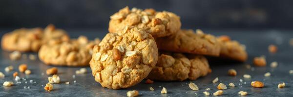 Freshly baked oatmeal cookies stacked on a dark surface with scattered oats photo