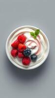 Delicious yogurt topped with fresh raspberries, blueberries, and blackberries in a white bowl photo