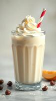 Creamy vanilla milkshake topped with whipped cream and a red striped straw on a marble countertop photo