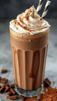 Creamy chocolate milkshake topped with whipped cream and chocolate shavings served in a tall glass with striped straws photo