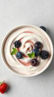 Creamy swirl of yogurt topped with fresh berries and mint on a gray surface photo